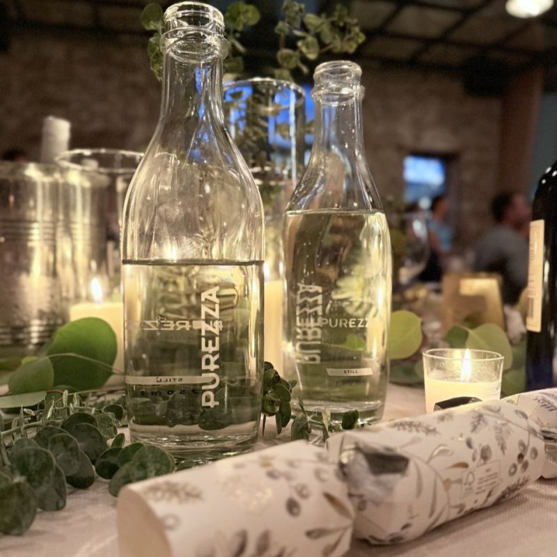 Elegant restaurant table with Purezza Premium Water served in reusable glass bottles